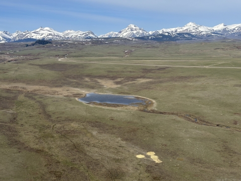 aerial view of a landscape with mountains and grasslands and a lake