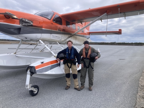 two people stand in front of an airplane