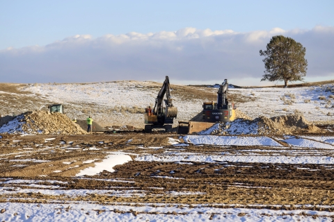 Two pieces of heavy equipment move and pile dirt at the Klamath Falls National Fish Hatchery. 