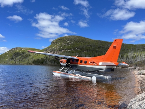 airplane floating on water with mountains in the background