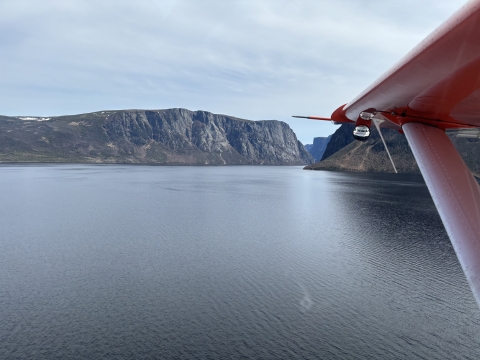 aerial view of airplane wing over water with mountains in the background