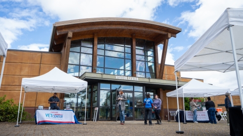 Photo of the front of Tualatin River National Wildlife Refuge visitors center. There are event tents set up and people talking.