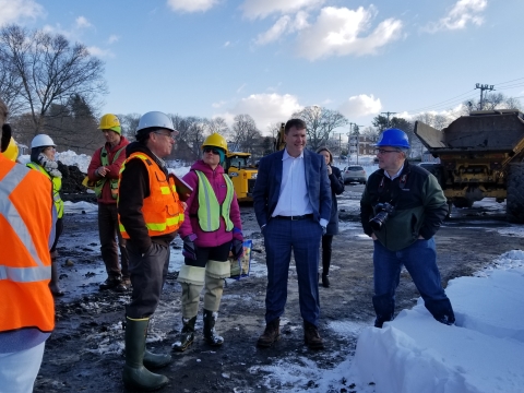 Four people stand in mud and snow at a construction site