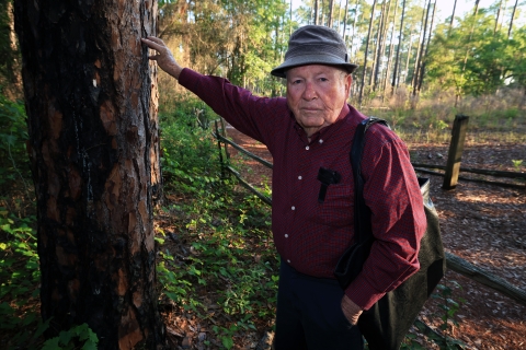 Joe Chesser stands next to a slash pine he planted on the property before the refuge took over the Homestead. He grew up to become a forester.