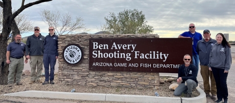 7 Arizona Game and Fish Department staff stand by Ben Avery Shooting Facility sign. 
