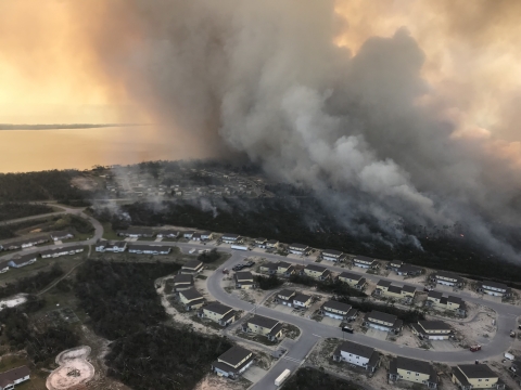 A prescribed fire burns near a housing area. The photo is taken from an aircraft.