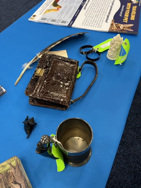 A feather, purse, ivory sculpture, and other items on a blue tablecloth