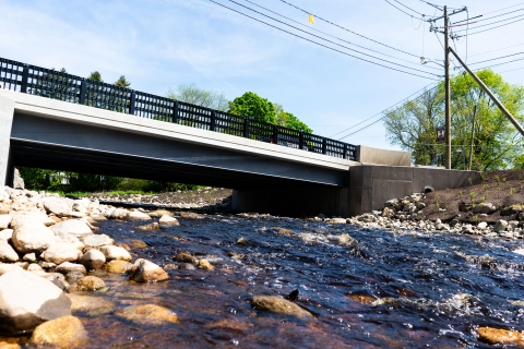 a concrete bridge stretches from bank to bank as a rocky river flows beneath