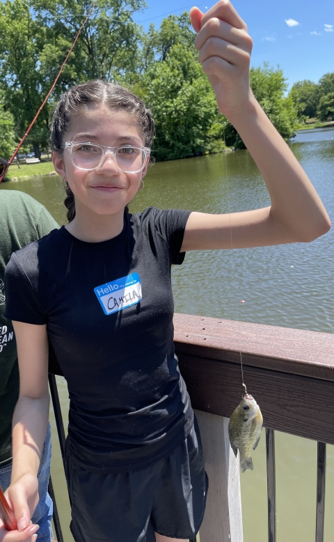 Youth poses with a fish they caught at the 2024 Cops and Bobbers fishing program as part of the Elizabeth Urban Wildlife Refuge Partnership