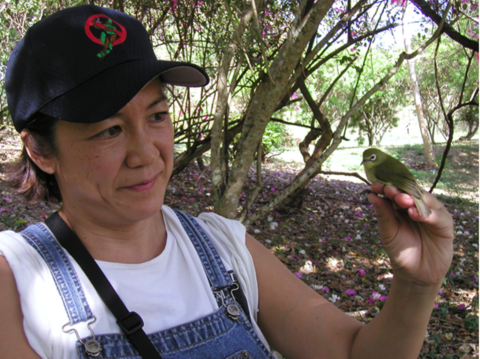 Marilet Zablan with bridled white-eye in a forest on Guam