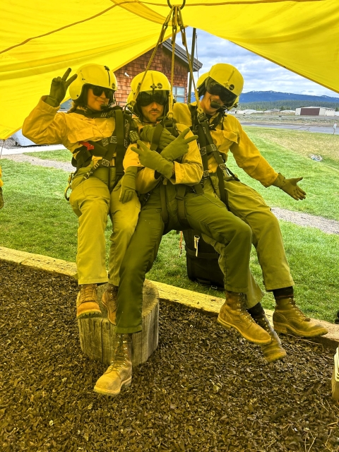 Three firefighters suspended shortly off the ground during practice pose for a photo.