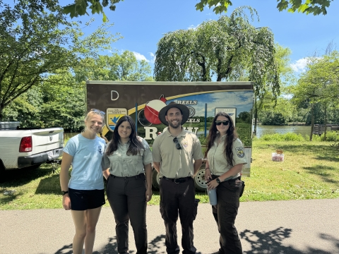 U.S. Fish and Wildlife Service staff pose in front of the Reels on Wheels (R.O.W.) mobile fishing trailer at the 2024 Cops and Bobbers fishing program as part of the Elizabeth Urban Wildlife Refuge Partnership