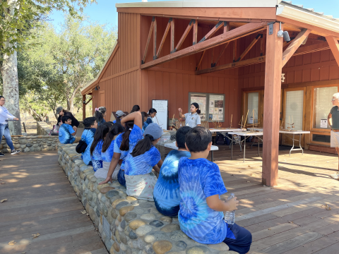 A group of students wearing matching blue t-shirts sitting on a bench