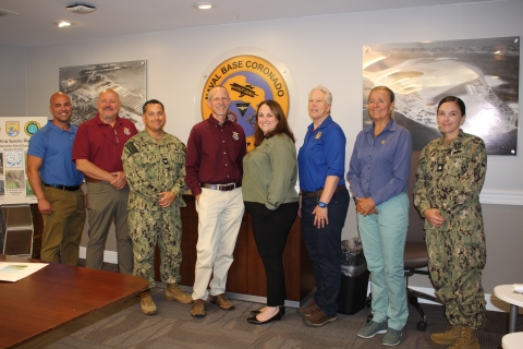 group of men and women pose for photo in conference room