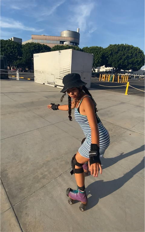 A woman wearing a black hat roller skates towards the camera