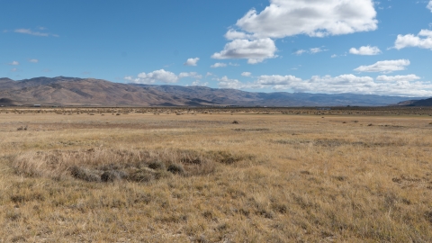 A sagebrush landscape extends out with mountains in the background