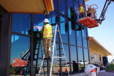 FWS Staff install bird safe glass film at the RMA NWR using both ladders and raised platforms to reach high windows