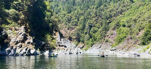 A group of people kayaking on a lake with mountains in the background