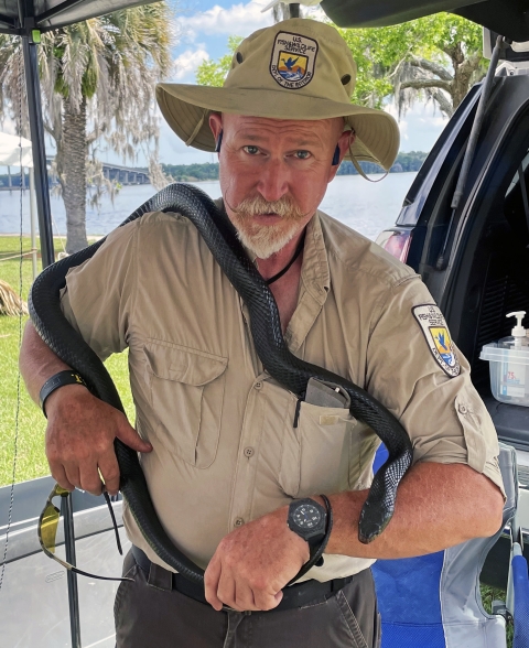 Tony Brady poses with an eastern indigo snake wrapped around his neck and waist. Brady is the deputy project leader at USFWS’ Welaka National Fish Hatchery, where they have been caring for the snakes since 2018.