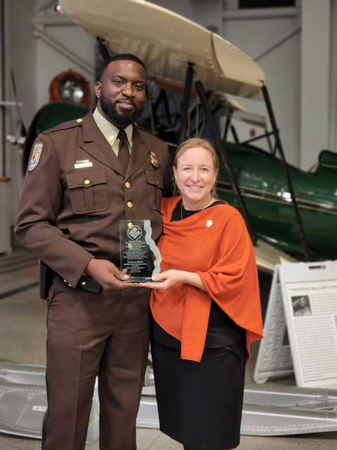 a man in uniform stands with a woman who is presenting him with an awardlding an award