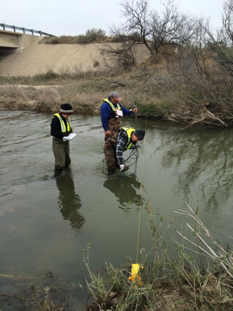 Image of 3 researchers in waders standing in a river