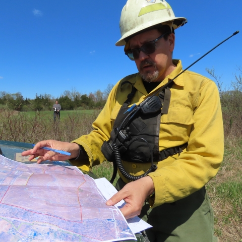 a man wearing yellow and a hard looks intently at a map