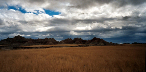 A grassland in front of large rock formations