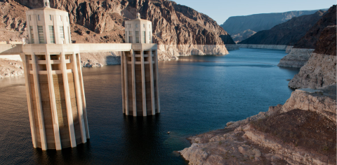 A lake surrounded by geologic rock formations, with 2 large cylindrical structures protruding from it 