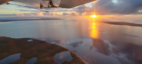 sunset of a coastal wetland with airplane wing framing 