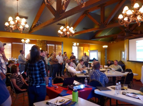 People gather around in a large room in front of a projected screen 