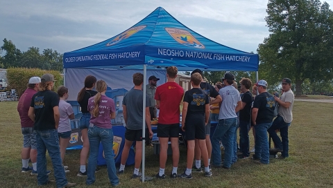 high school students gather under a display tent at an outdoor career fair