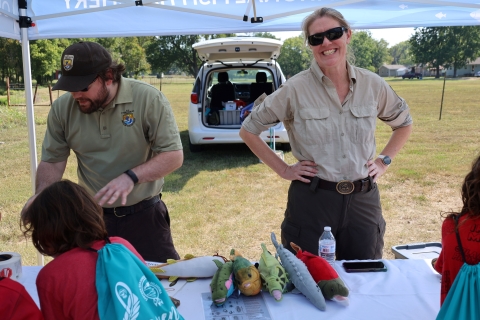 USFWS staff educate students about fish and aquatic resources in the shade of an outdoor canopy