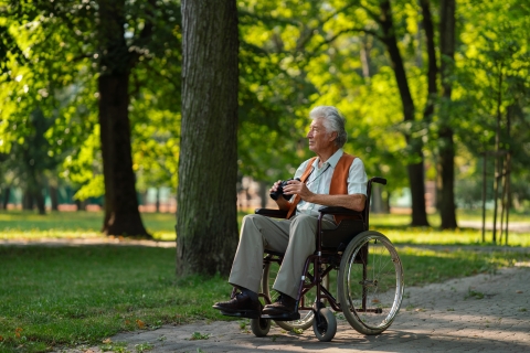 Senior man in wheelchair with binoculars wildlife watching