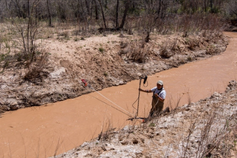 A researcher stands in a shallow brown body of water