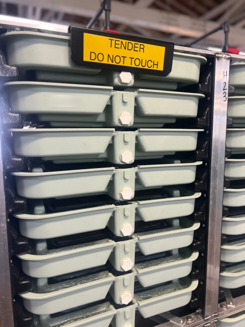 Eight trays stacked on top of each other with a yellow sign at the top that reads, "Tender do not touch".