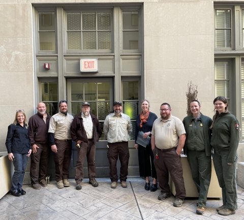 nine people stand in front of doorway as they work to make windows bird safe