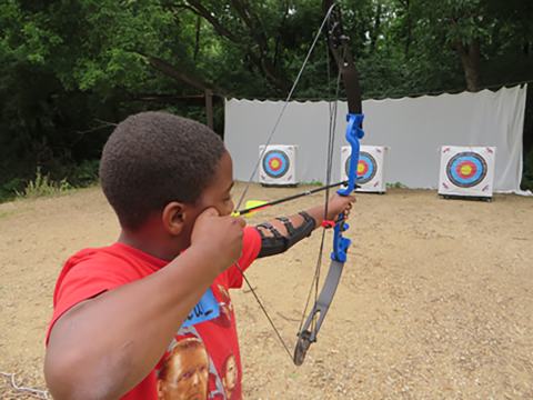 Student aiming a bow at the target
