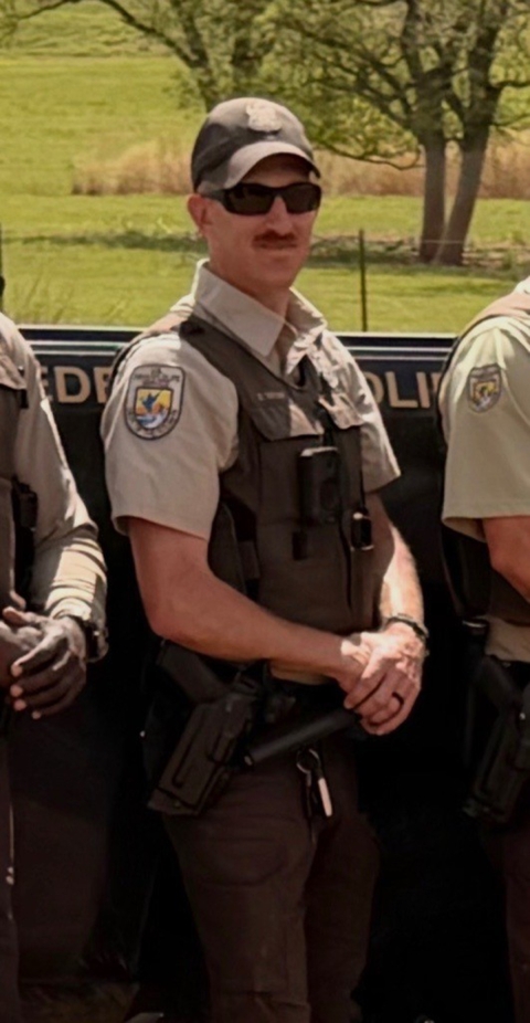Officer David Taylor, standing with hands held at his waist, alongside other officers.