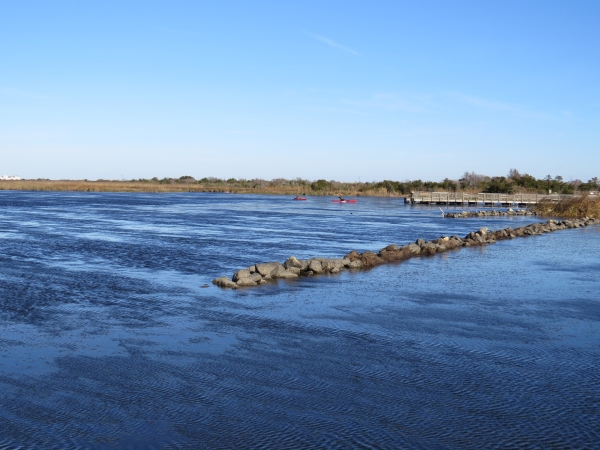 Two kayakers on Back Bay; fishing dock and erosion control breakwaters are also visible