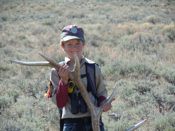 A young boy holing a huge antler shed that's about the same size as he is