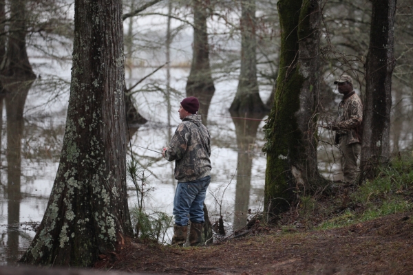 An image of two fishermen bank fishing wearing camo.