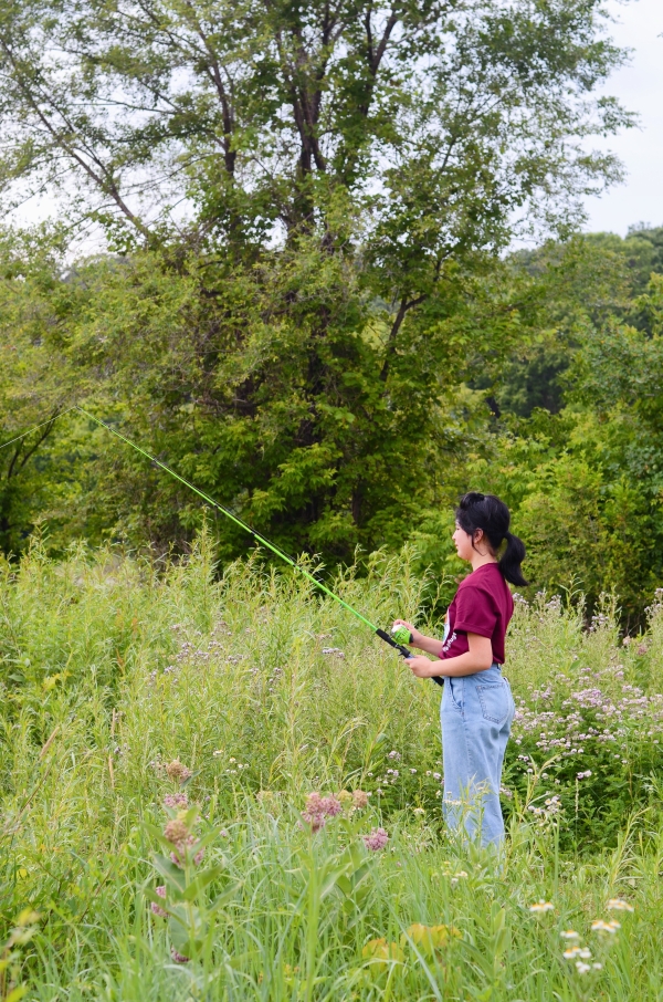 Side view of youth fishing near flowered vegetation