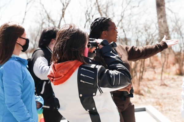 Park Ranger leading interpretive program pointing towards birds with people using binoculars