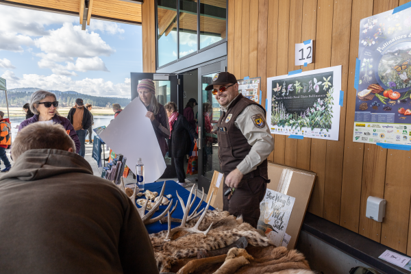A ranger in a FWS uniform smiles at visitors from behind a table