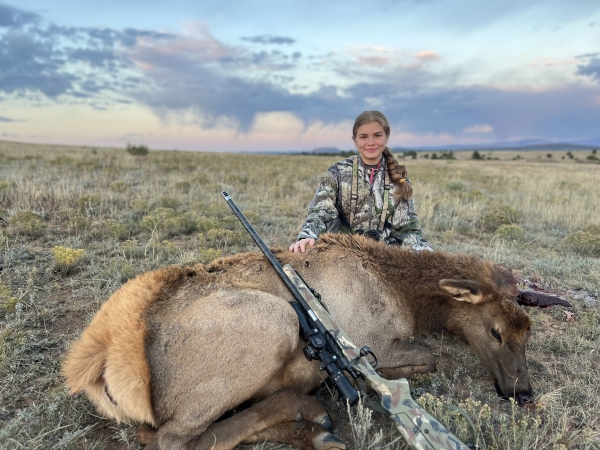 A young girl sitting with her harvested elk cow