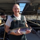 a man in waders hold a rainbow trout