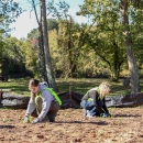 Two people, back-to-back, planting in cleared soil