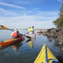 group of kayakers and canoers boating along edge of island