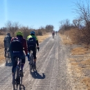 cyclists ride along a dirt road in the desert