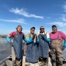 4 biologists standing on a boat in a wetland and one biologist is holding a duck